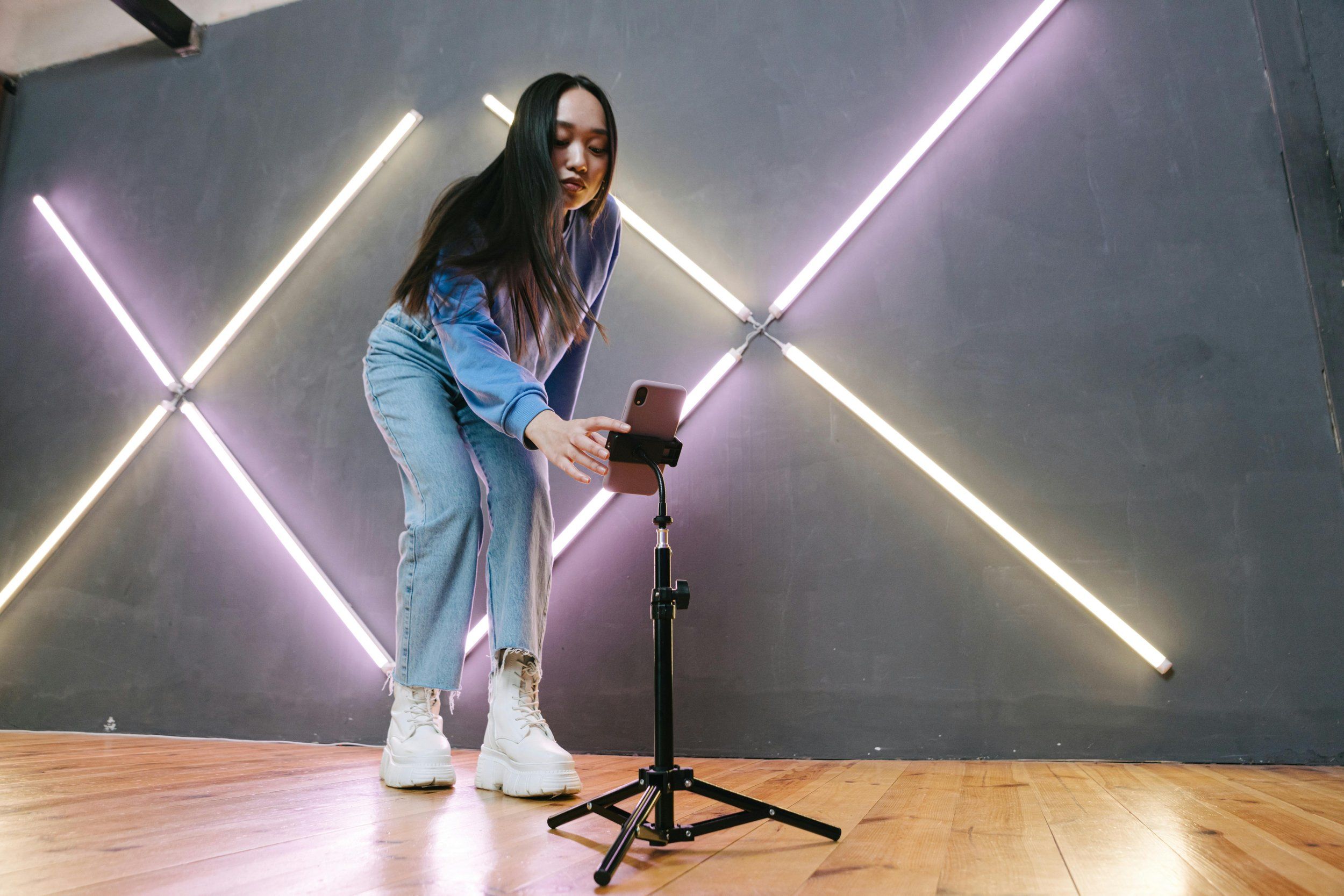 Creator filming herself on a phone tripod under neon lights