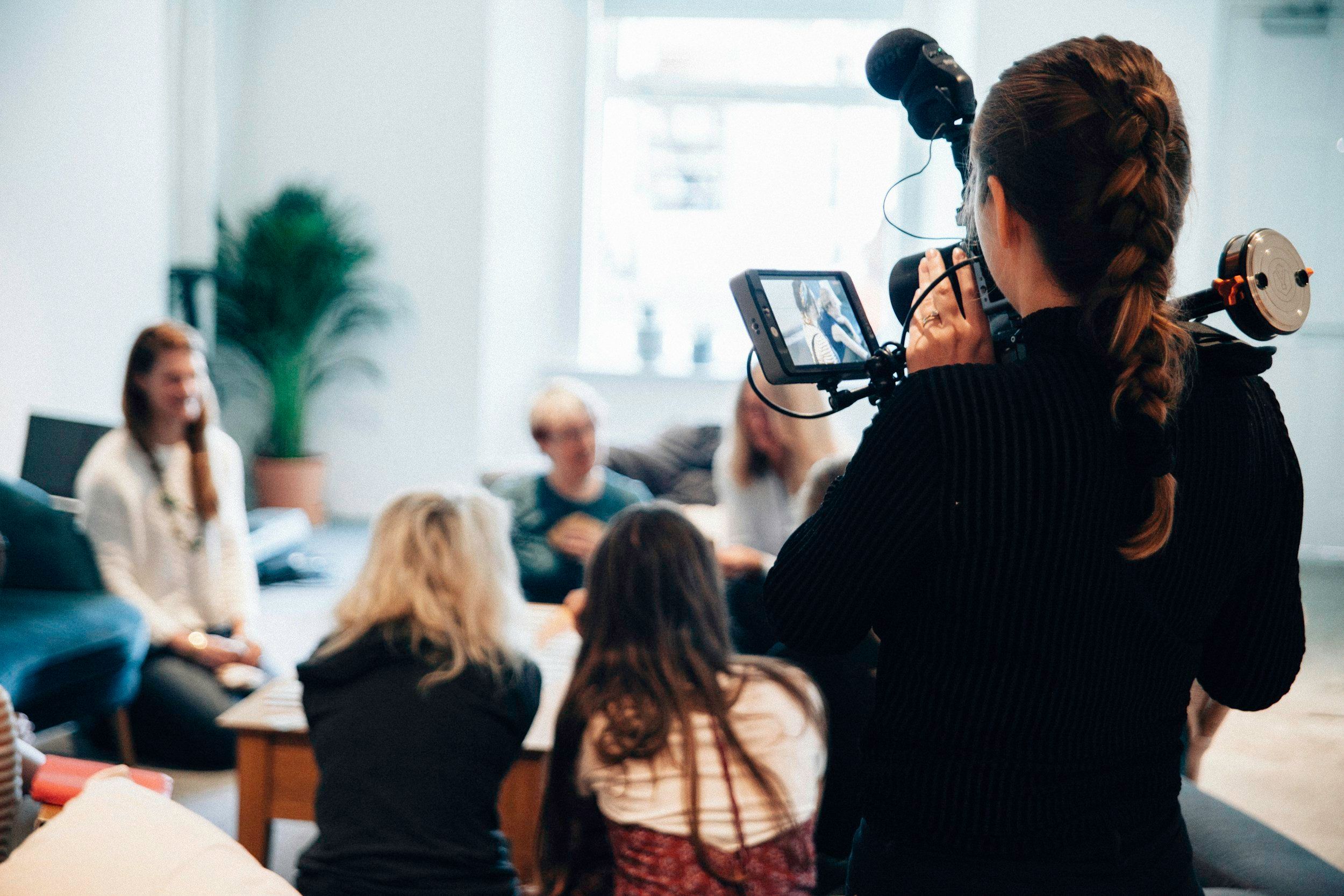 Videographer with a camera rig filming a team meeting