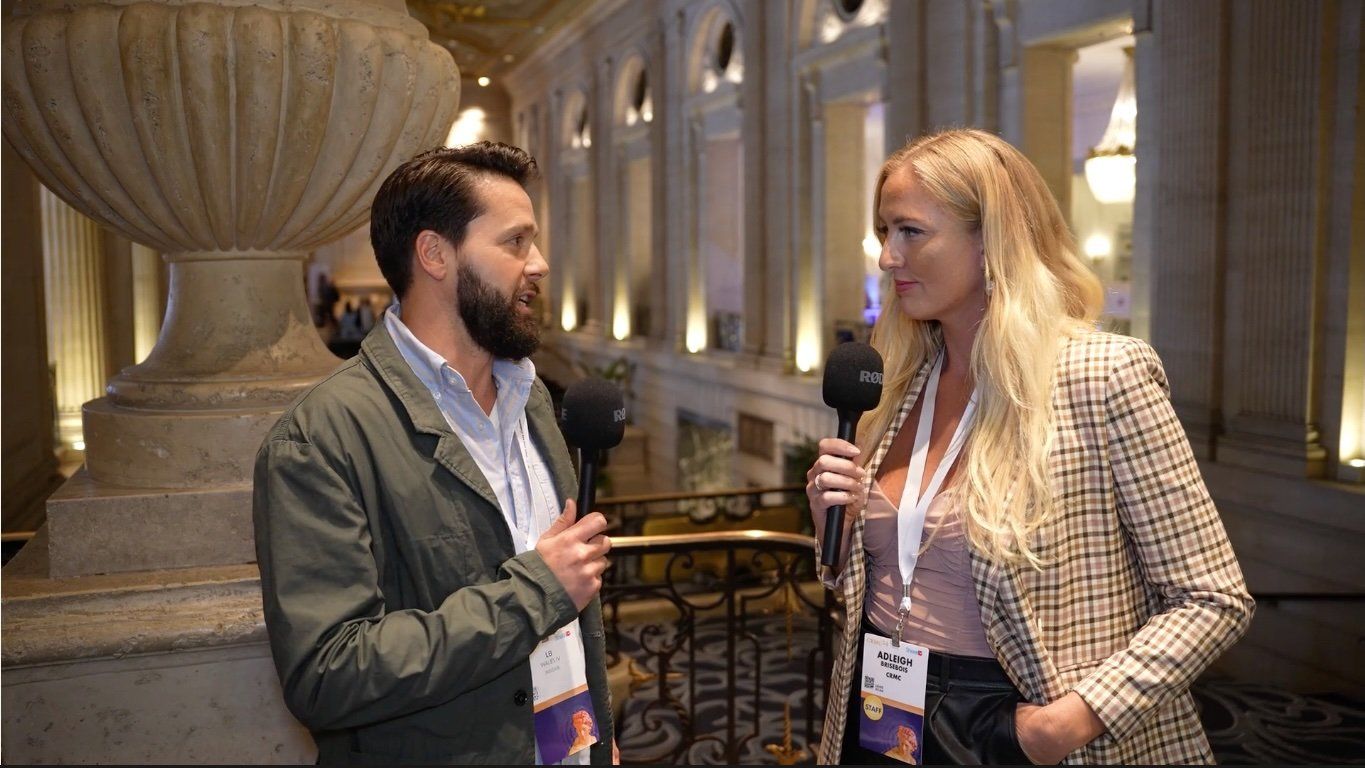 Adleigh interviewing an attendee in an ornate hotel hallway