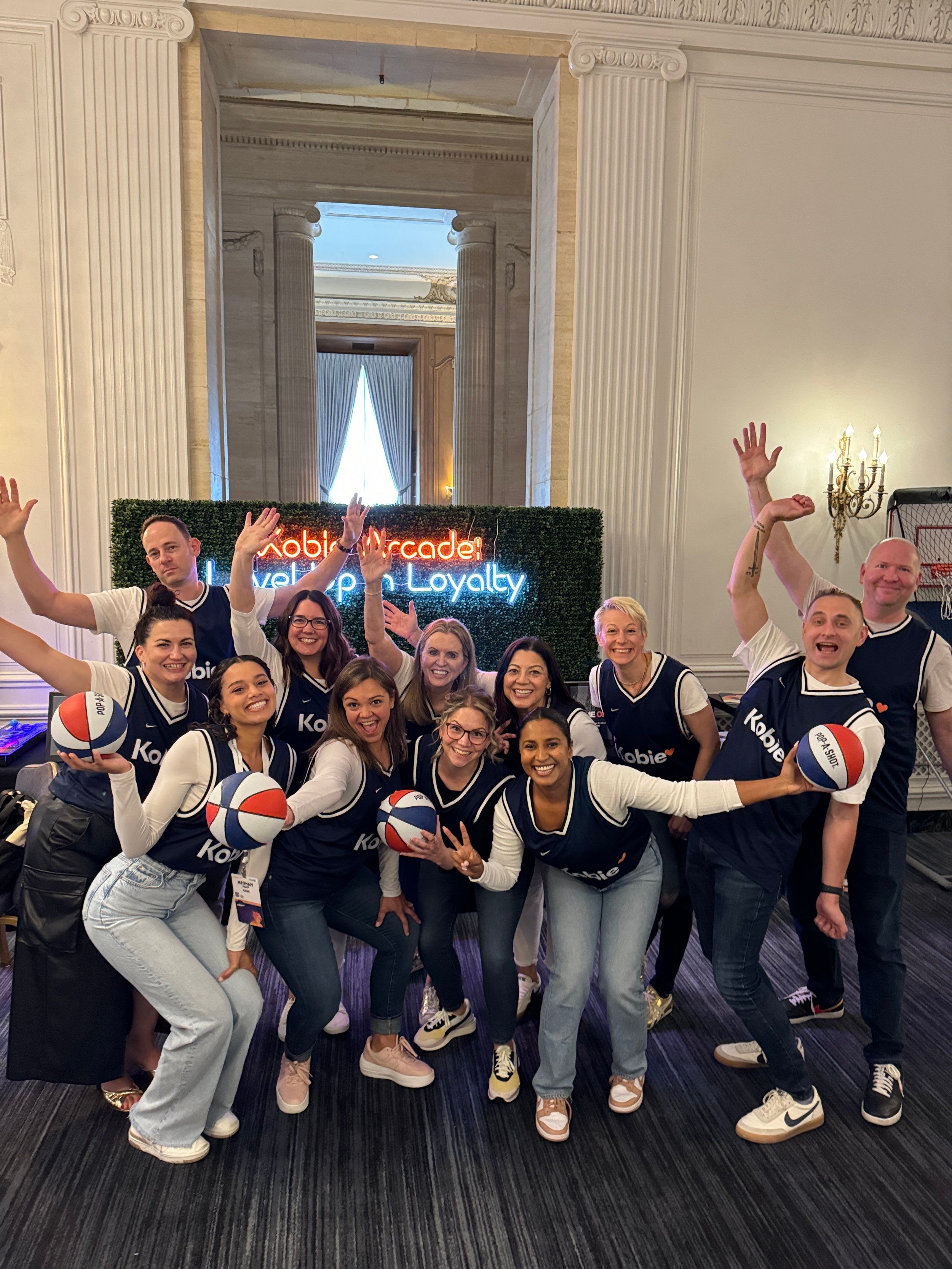Event team posing with basketballs in front of a neon sign