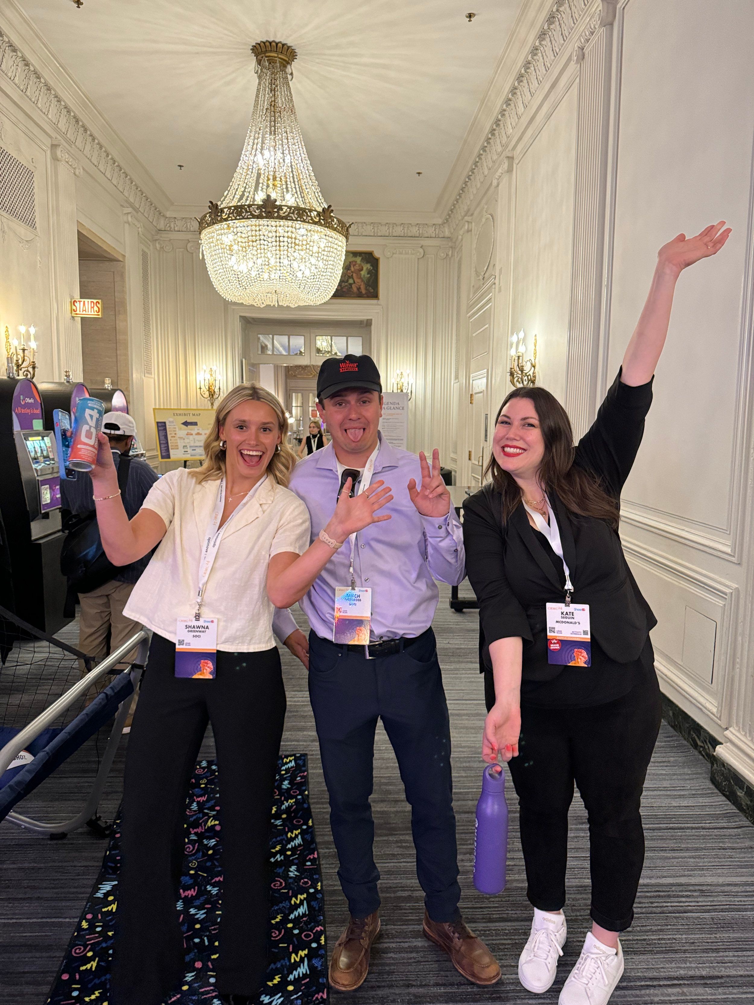 Three event guests posing under a chandelier