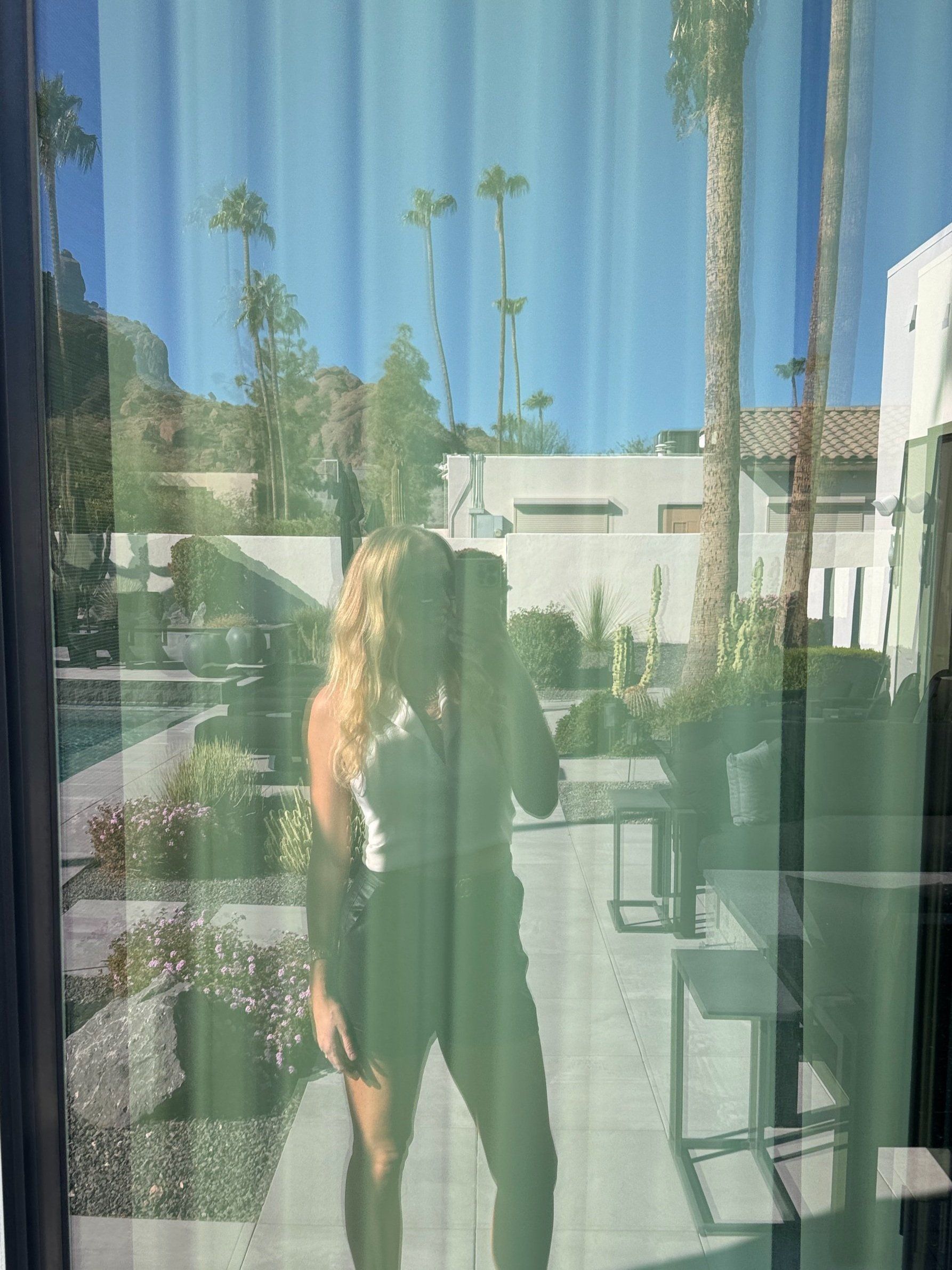 Selfie reflected in a window with palm trees behind